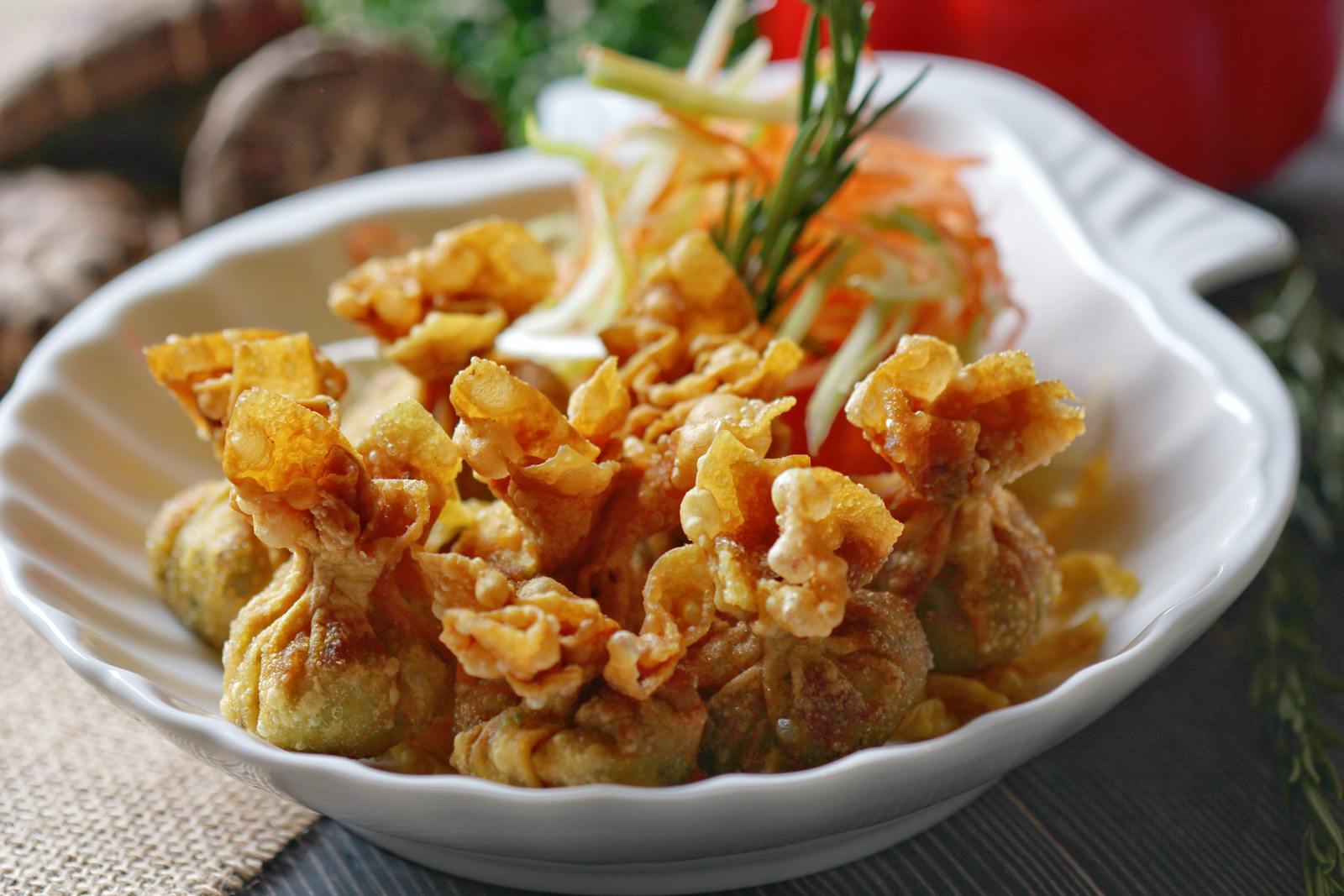 Delicious crispy shrimp wontons served with fresh garnish in an elegant setting, perfect for food lovers.